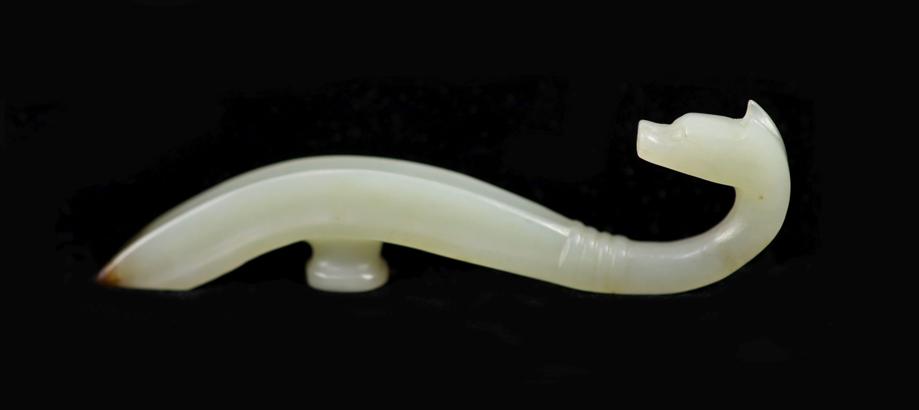 A Chinese pale celadon and brown jade belt hook, 9 cm long